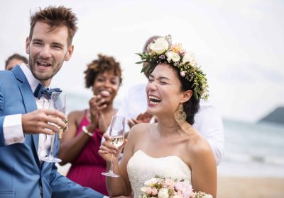 Joyful wedding speech on the beach with smiling bride and guests celebrating.