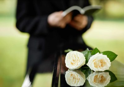 Person reading a speech outdoors with roses on a reflective surface.