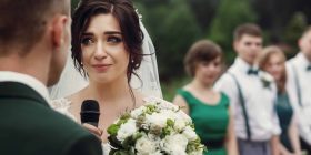 Bride giving emotional wedding speech during outdoor ceremony.