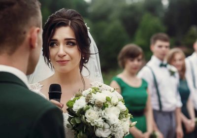 Bride giving emotional wedding speech during outdoor ceremony.